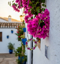 Necklace with pink flowers against a white wall and outdoor background