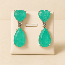 	Elegant drop earrings displayed on satin cream stand