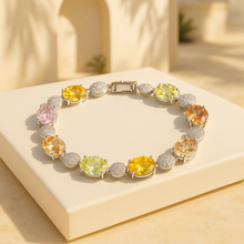 Luxury multi-stone sterling silver healing bracelet by Curación Holística featuring yellow, pink, green, and orange gemstones on a satin cream background with Spanish villa backdrop.
