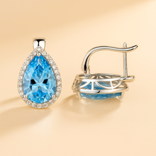 Earrings placed on satin background with white quartz scattered for luxury detail