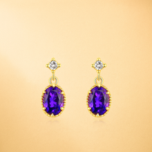 “Close-up of gold-plated amethyst earrings with white quartz on a velvet display”