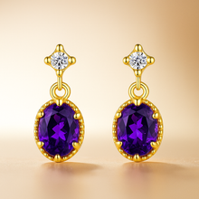 Close-up of gold-plated amethyst earrings with white quartz on a velvet display”