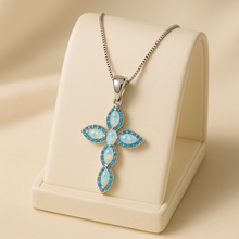 “Handmade sterling silver cross necklace featuring vibrant opals and delicate aquamarines, exclusive statement jewelry by Curación Holística displayed in soft luxury lighting.”