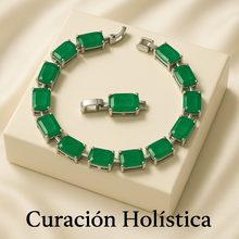 “Handmade sterling silver bracelet with rectangular natural emeralds displayed on a cream stone surface with vibrant Spanish scenery in the background – exclusive boho statement jewelry by Curación Holística.”
