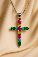 “Handmade multi-gemstone cross necklace on luxury satin display”