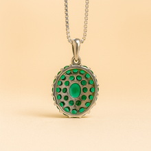 Natural emerald oval pendant glowing in professional jewelry lighting