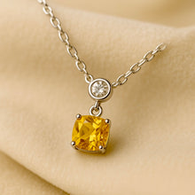 “Small cushion-cut citrine and white quartz pendant necklace in sterling silver by Curación Holística, displayed on soft cream velvet with luxury studio lighting.”