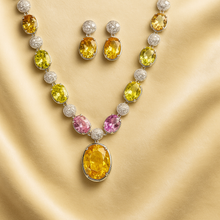Multi-gemstone necklace set on cream satin background with earrings displayed.