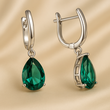 Handheld shot of sterling silver emerald earrings, showing gemstone clarity and craftsmanship