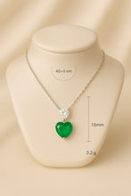 “Exclusive handmade jewelry: sterling silver necklace with a heart-shaped nano-emerald and teardrop white quartz pendant, photographed under soft sunlight in a Spanish villa.”