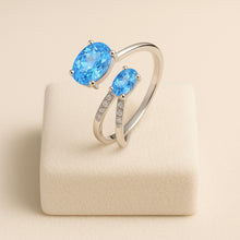 Fine silver ring with oval-cut gemstones presented on satin background