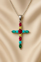 “Close-up of colorful multi-stone cross necklace against creamy satin background”