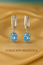 Sterling silver hoop earrings with oval-cut aquamarine gemstones on satin gold background — Curación Holística