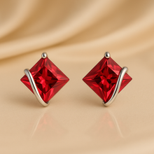 Princess-cut red ruby stud earrings on cream background