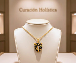 Gold necklace with a black and green pendant on a mannequin bust in front of a 'Curación Holástica' sign.