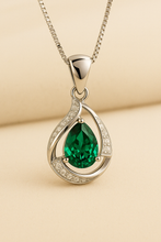Sterling silver teardrop emerald pendant on satin cream background