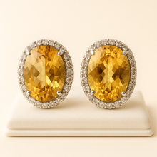 Natural citrine earrings with halo diamonds on satin cream background