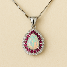 “Detailed close-up of the handmade fire opal necklace encircled by ruby accents in sterling silver setting.”