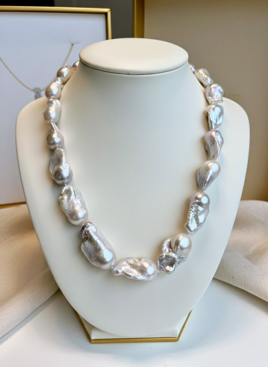 Pearl necklace on a white mannequin bust with a neutral background