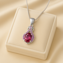 Elegant ruby pendant necklace with pink gemstone accents on cream jewelry box.”