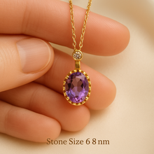 Close-up of amethyst and quartz gold pendant necklace in hand