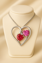 Close-up of handmade double heart ruby and rose topaz pendant in sterling silver gold plating.”
