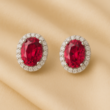 	“Elegant ruby and white quartz stud earrings displayed on luxurious satin background.”