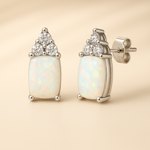 Close-up of sterling silver opal and quartz earrings on a satin background