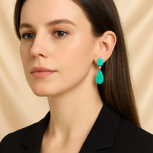 Hand holding bright blue gemstone earrings for women