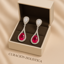 Curación Holística red earrings photographed on cream fabric