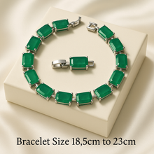 “Handmade sterling silver bracelet with rectangular natural emeralds displayed on a cream stone surface with vibrant Spanish scenery in the background – exclusive boho statement jewelry by Curación Holística.”
