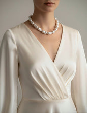 White dress with a pearl necklace on a neutral background