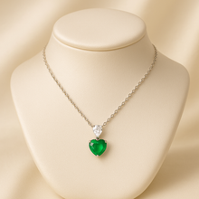 “Natural nano-emerald heart pendant and white quartz necklace in fine sterling silver, handmade and exclusive design by Curación Holística, displayed with Spanish architecture.”