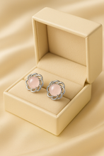 “Timeless sterling silver and rose quartz stud earrings on luxury satin background.”