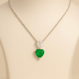 “Elegant emerald heart pendant necklace with a white quartz accent in a sterling silver setting, exclusive design by Curación Holística, photographed in a Mediterranean-inspired backdrop.”