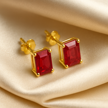 Close-up view of gold-plated sterling silver ruby earrings with vivid red stones.”