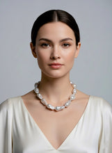 Woman wearing a pearl necklace against a plain background