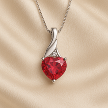 Close-up of ruby heart necklace with sterling silver swirl design