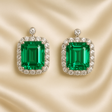 Sterling silver emerald statement earrings on cream satin background
	