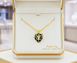 Gold necklace with a black and green pendant in an open jewelry box.