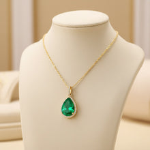 Gold necklace with a green teardrop pendant on a mannequin bust.