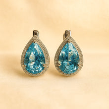 	Earrings placed on satin background with white quartz scattered for luxury detail