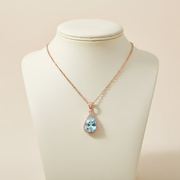 Necklace with a blue teardrop pendant on a mannequin bust against a beige background