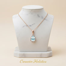 Necklace with a teardrop-shaped pendant on a marble bust, branded 'Curacion Holistica'.